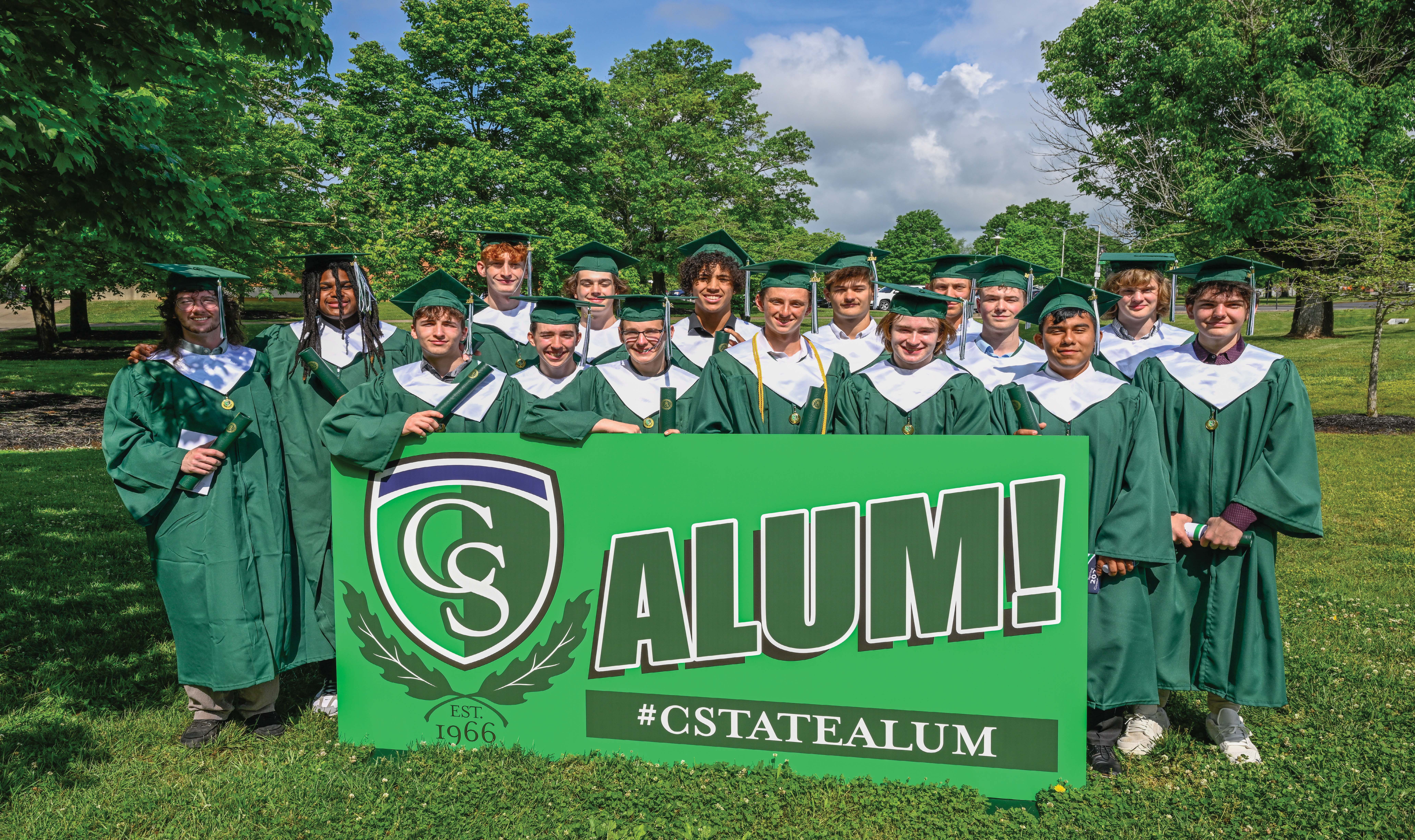 Students at Graduation with Alumni Sign